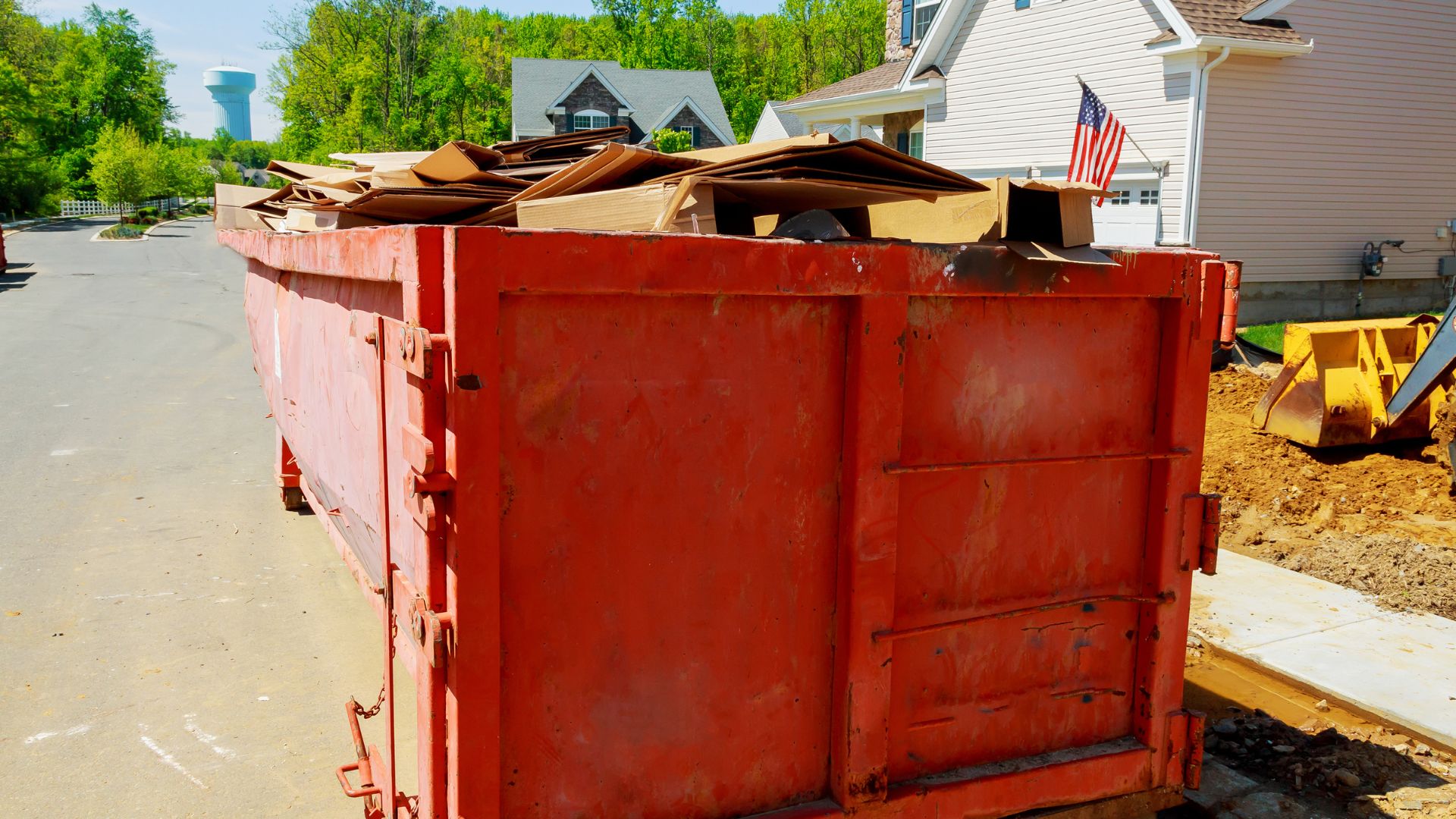 Large red dumpster filled with construction debris in residential neighborhood